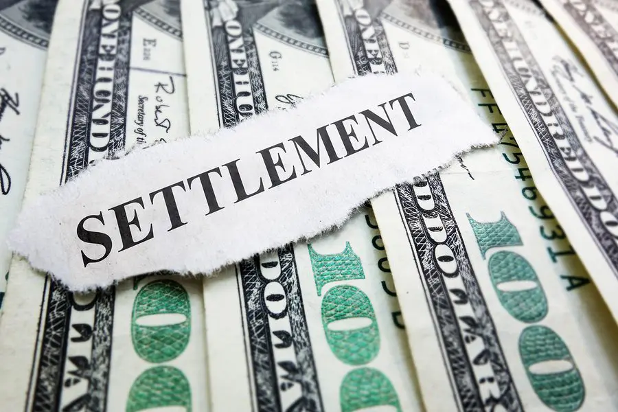 Piece of Paper that Says Settlement Resting On Money