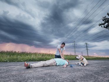 Resuscitating Man On Road With Dog