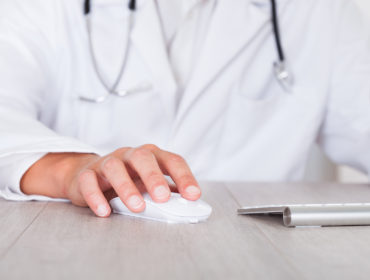 Close-up Of Male Doctor's Hand Using Computer for EHR